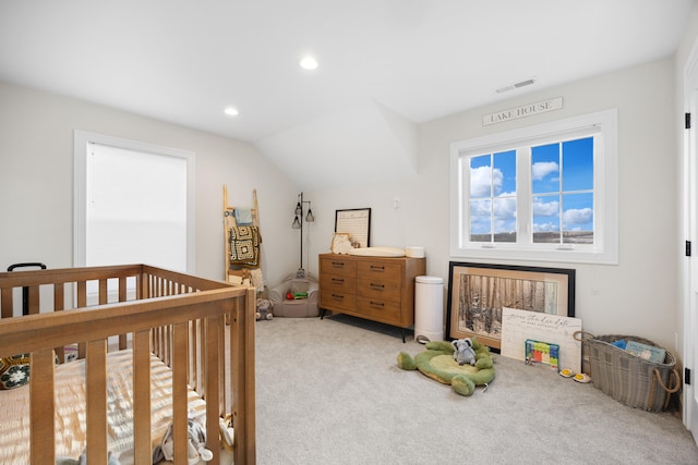 bedroom with lofted ceiling, light colored carpet, and a crib