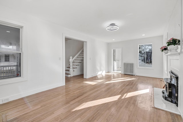 unfurnished living room featuring radiator heating unit and light hardwood / wood-style flooring