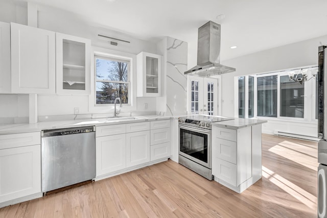 kitchen with island range hood, white cabinets, stainless steel appliances, and light wood-type flooring