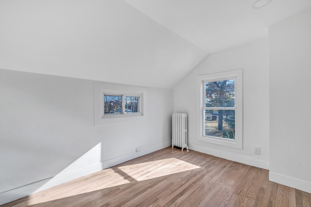 additional living space featuring radiator heating unit, light hardwood / wood-style floors, and lofted ceiling