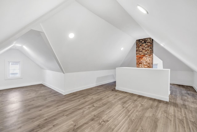 additional living space with light hardwood / wood-style flooring and vaulted ceiling