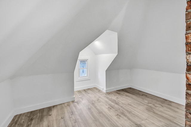 bonus room with vaulted ceiling and light wood-type flooring