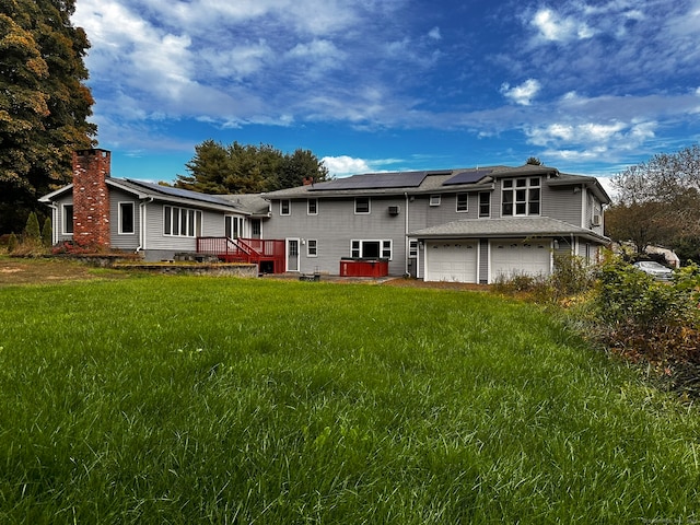 back of property featuring solar panels, a yard, and a garage