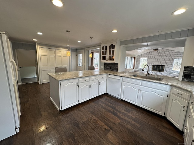 kitchen with dark wood-style flooring, white cabinetry, a sink, white appliances, and a peninsula