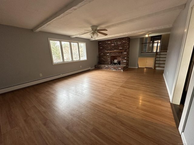 unfurnished living room with baseboards, a ceiling fan, stairway, wood finished floors, and baseboard heating