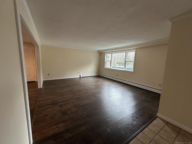 spare room featuring ornamental molding, baseboard heating, wood finished floors, and baseboards