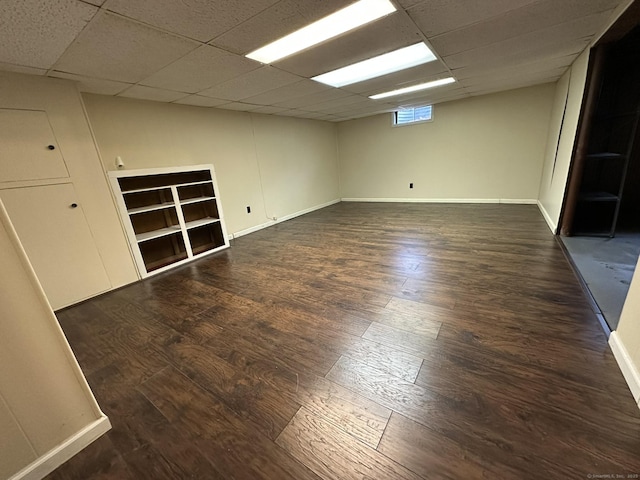 empty room featuring a paneled ceiling, baseboards, and wood finished floors