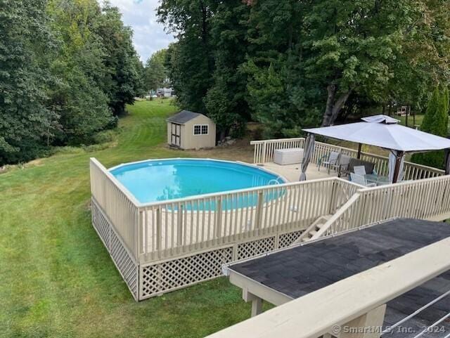 view of swimming pool featuring a yard, a storage shed, and a deck