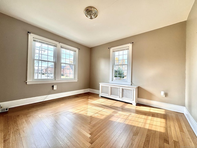 empty room featuring radiator, hardwood / wood-style flooring, and plenty of natural light