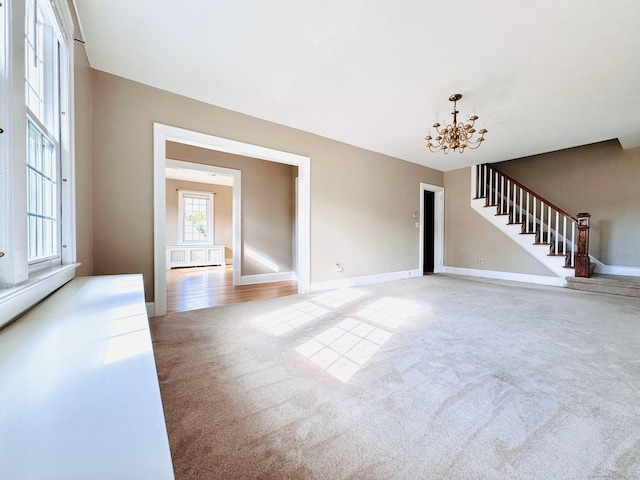 unfurnished living room with a notable chandelier and light colored carpet