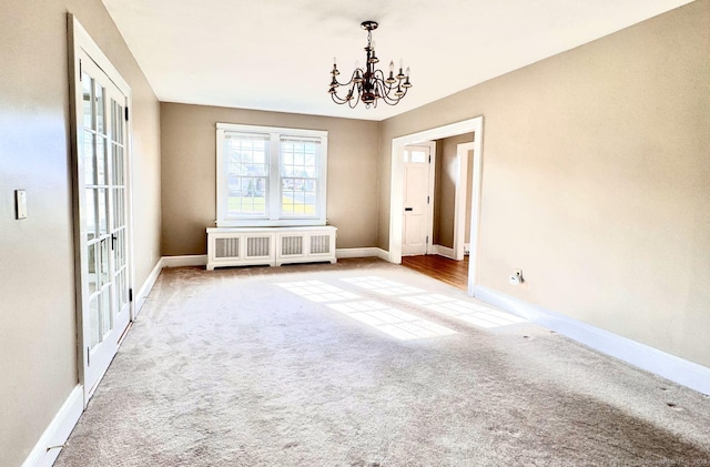 carpeted spare room featuring a notable chandelier, french doors, and radiator