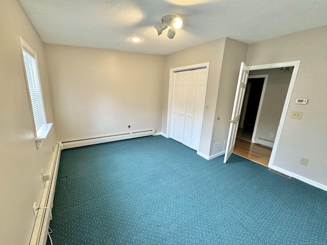 unfurnished bedroom featuring a closet, a baseboard heating unit, a textured ceiling, and ceiling fan