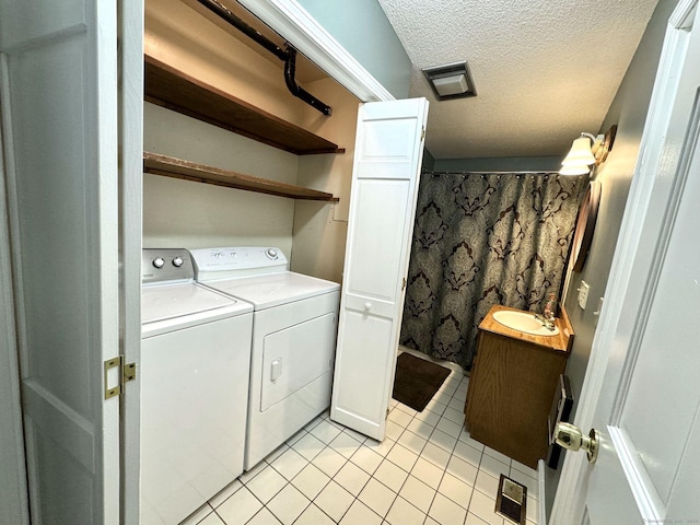 washroom with sink, a textured ceiling, washing machine and clothes dryer, and light tile patterned floors