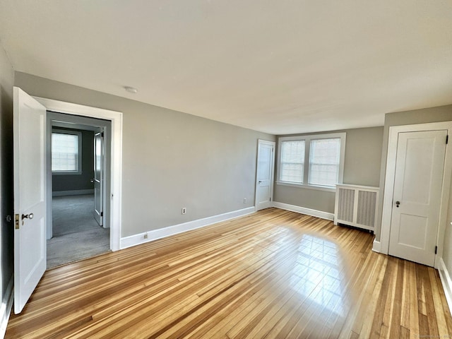 spare room featuring light hardwood / wood-style flooring, a healthy amount of sunlight, and radiator