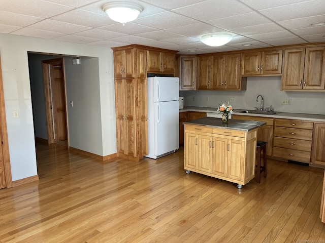 kitchen featuring a paneled ceiling, sink, light hardwood / wood-style floors, white fridge, and a center island