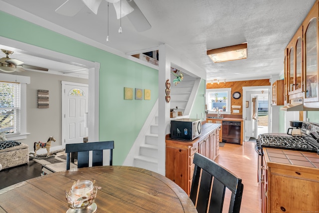 dining room with wooden walls, a textured ceiling, sink, and light wood-type flooring