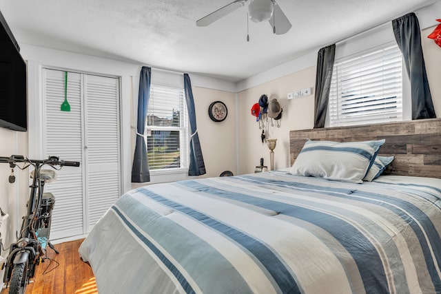 bedroom with a closet, a textured ceiling, wood-type flooring, and ceiling fan