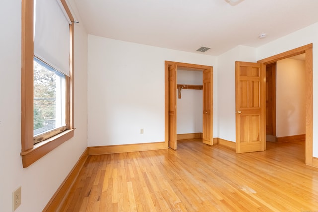 unfurnished bedroom with light hardwood / wood-style flooring and a closet