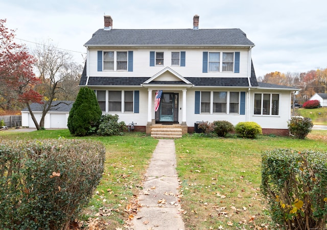 view of front of property with a garage, a front lawn, and an outdoor structure