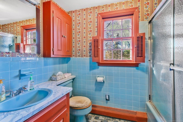 full bathroom with combined bath / shower with glass door, toilet, tile walls, and vanity