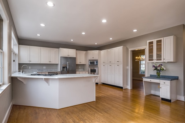 kitchen with white cabinets, a breakfast bar, kitchen peninsula, and appliances with stainless steel finishes