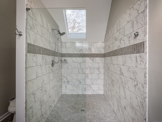 bathroom featuring tiled shower, toilet, and vaulted ceiling