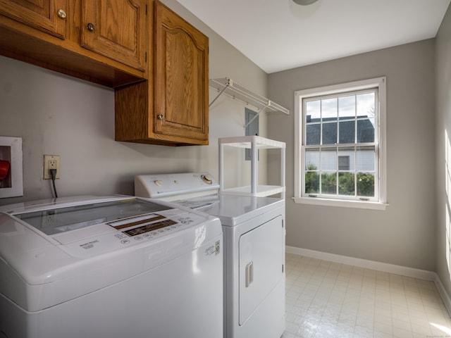 clothes washing area with washing machine and dryer and cabinets