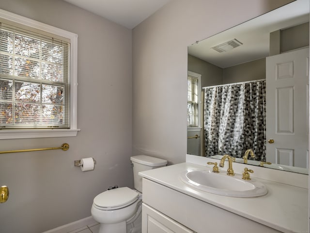 bathroom with toilet, vanity, and tile patterned flooring