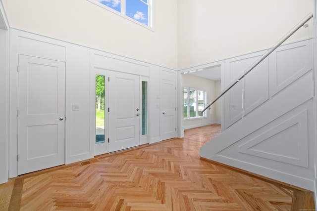 foyer entrance with a towering ceiling and light parquet flooring