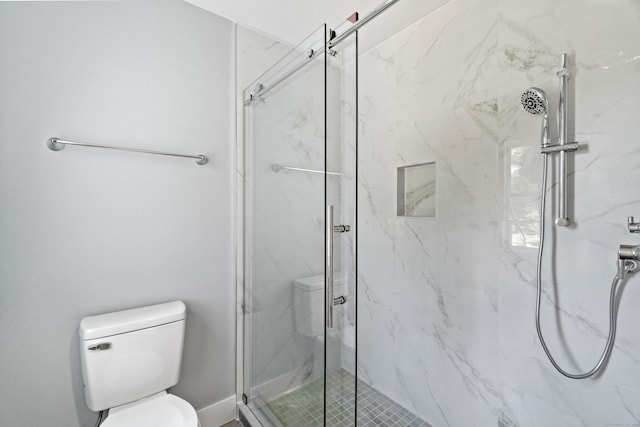 bathroom featuring a shower with shower door and toilet