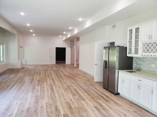 kitchen featuring white cabinetry, light hardwood / wood-style flooring, backsplash, and stainless steel refrigerator with ice dispenser