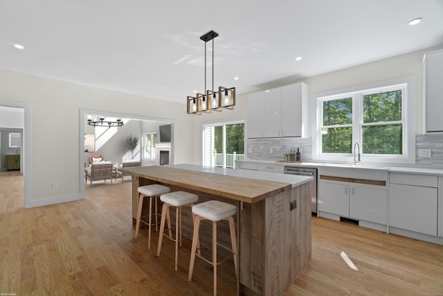 kitchen with a wealth of natural light, a center island, white cabinetry, and light wood-type flooring