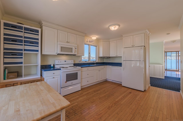 kitchen with ornamental molding, a wealth of natural light, white cabinets, and white appliances