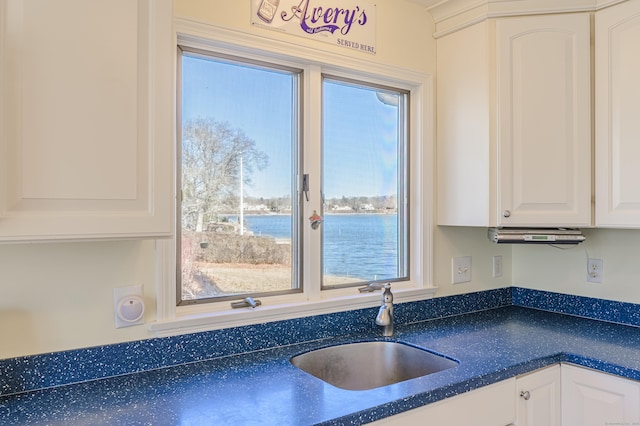 kitchen featuring a healthy amount of sunlight, a water view, sink, and white cabinets