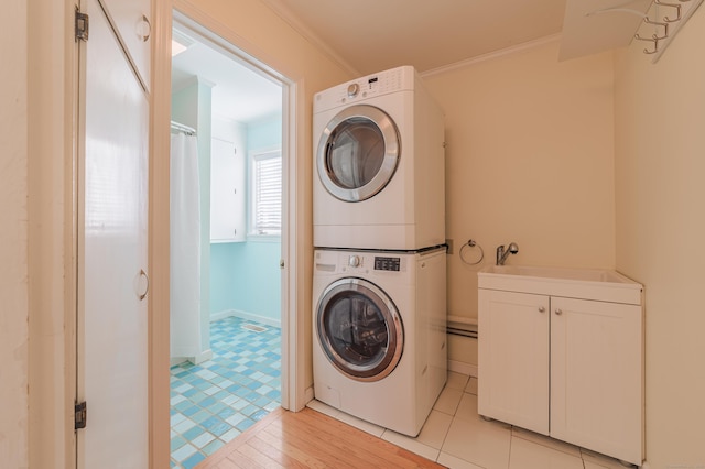 washroom featuring crown molding, cabinets, and stacked washer / dryer