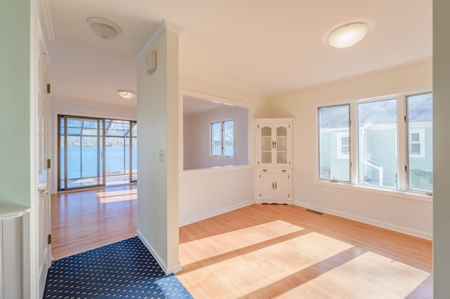 interior space featuring crown molding, a water view, and light hardwood / wood-style flooring