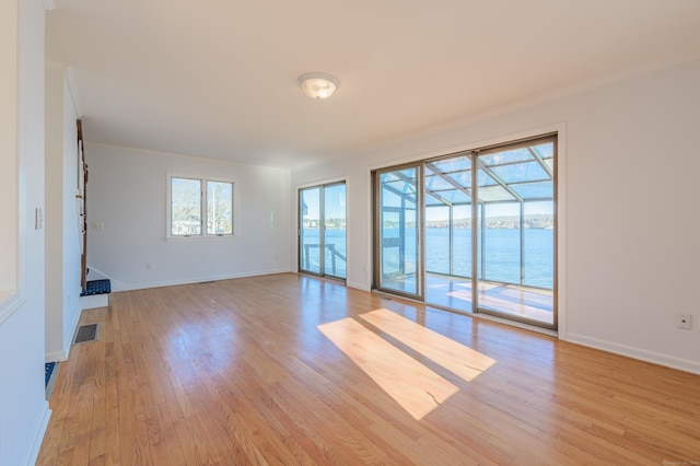 unfurnished living room with a water view, crown molding, and light hardwood / wood-style floors