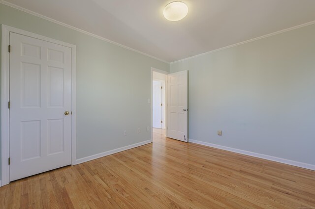 spare room featuring ornamental molding and light wood-type flooring