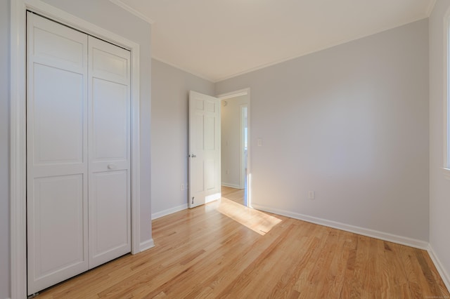 unfurnished bedroom featuring crown molding, light wood-type flooring, and a closet