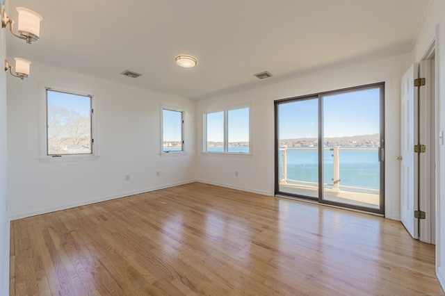 spare room with a water view and light hardwood / wood-style flooring