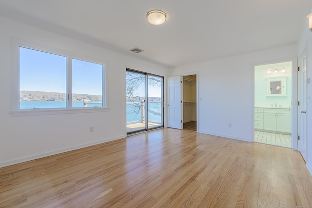 empty room featuring a water view and light hardwood / wood-style floors