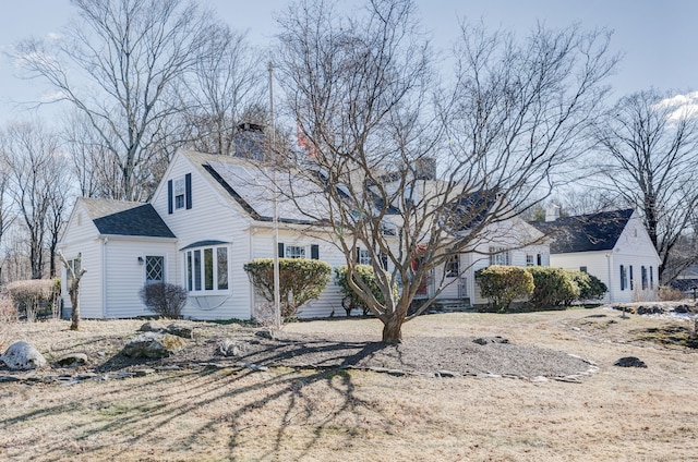 view of front of home with roof with shingles and solar panels