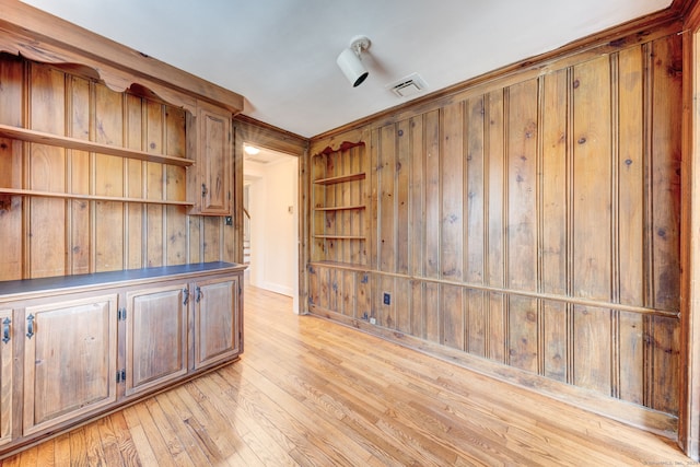 unfurnished office featuring light wood-style floors, visible vents, and wood walls