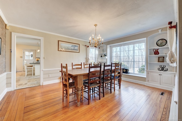 dining space featuring a wealth of natural light, light wood-type flooring, crown molding, and an inviting chandelier