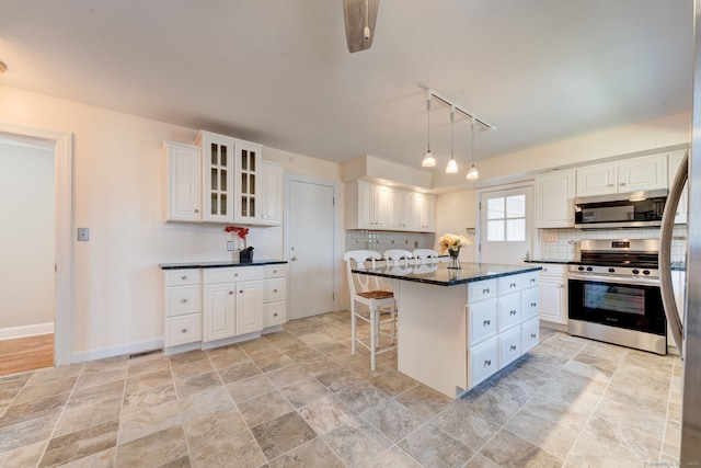 kitchen with appliances with stainless steel finishes, white cabinets, and backsplash