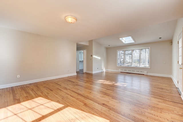 unfurnished room with a skylight, baseboards, a baseboard heating unit, and light wood finished floors