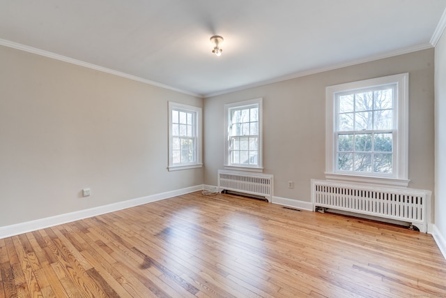 spare room with radiator heating unit, baseboards, wood-type flooring, and crown molding