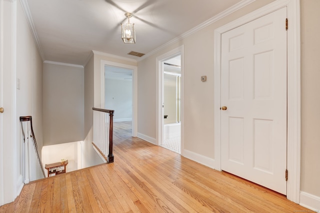 corridor with visible vents, ornamental molding, an upstairs landing, light wood-type flooring, and baseboards