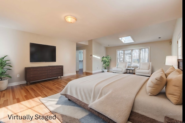 bedroom featuring a skylight, wood finished floors, and baseboards