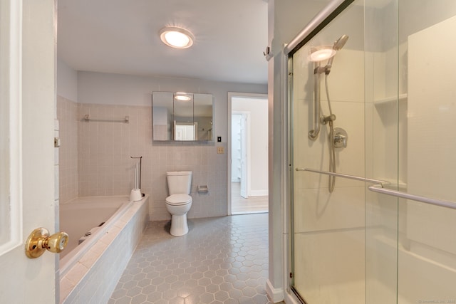 bathroom featuring a relaxing tiled tub, toilet, tile patterned flooring, an enclosed shower, and tile walls